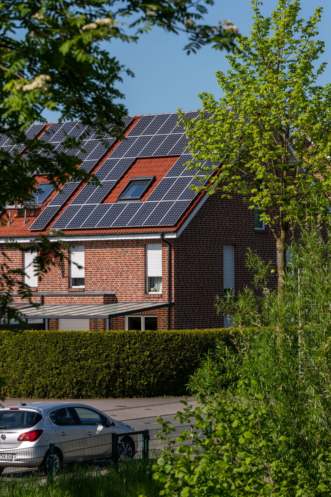 Woning met zonnepanelen op het dak, omringd door groen
