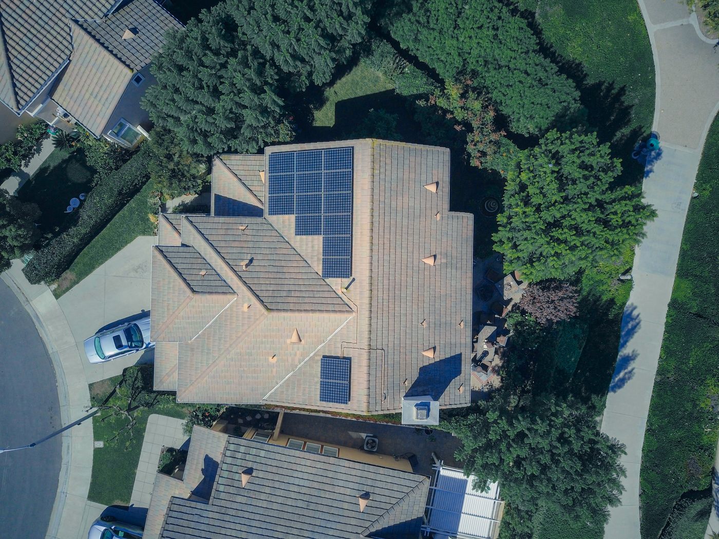 Bovenaanzicht van een woning met zonnepanelen, omgeven door groen