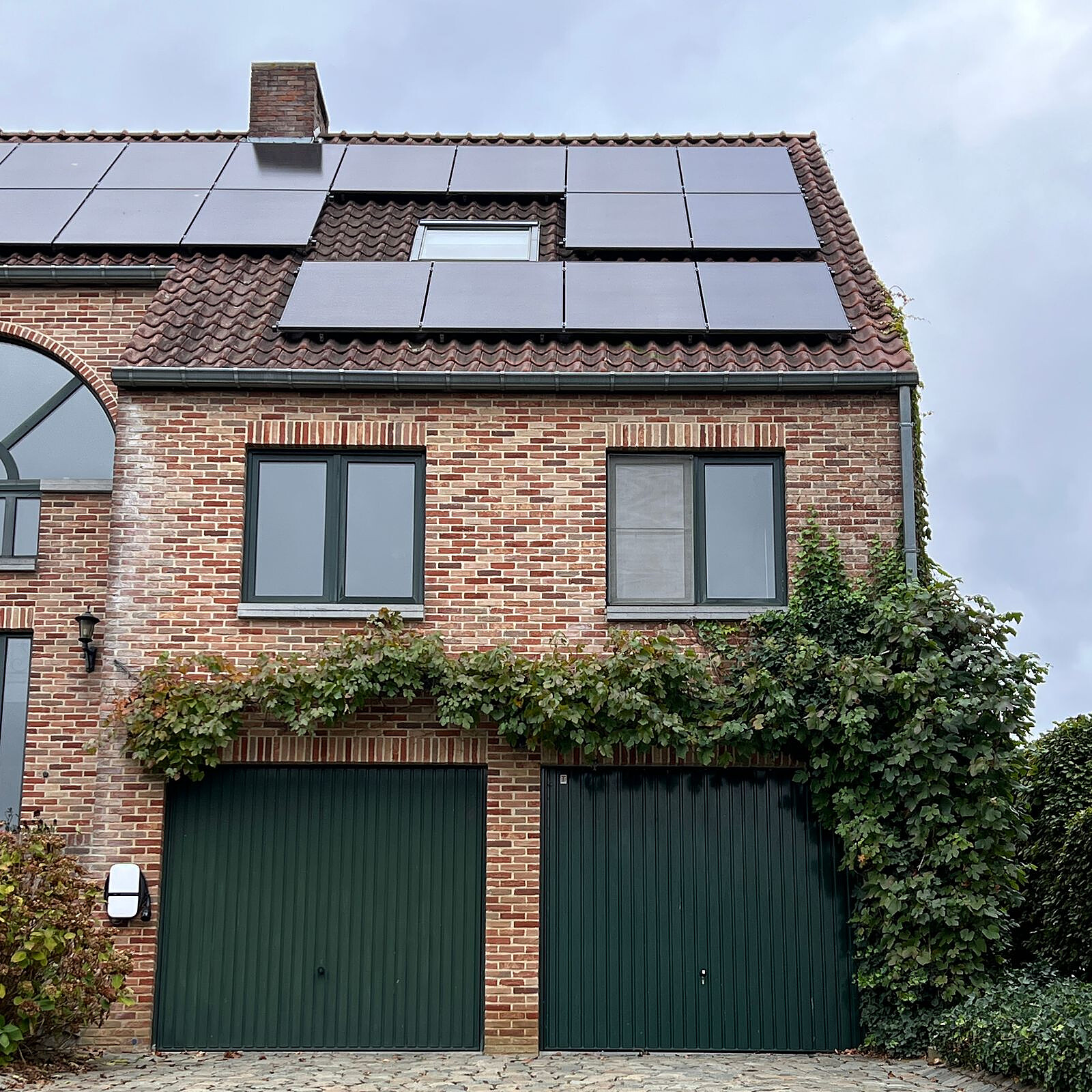 Bakstenen huis met zonnepanelen en klimwanden van klimop